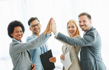 A group of young business people celebrating in the office with high ficeの写真素材