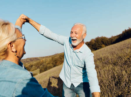 Happy active senior couple having fun dancing outdoors