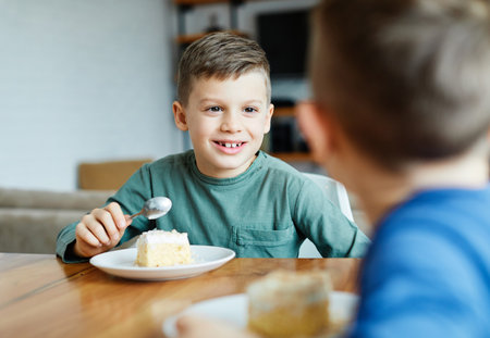 Portrait of two brothers eating cake at homeの写真素材