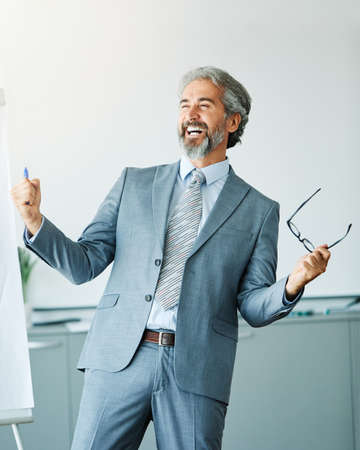 Portrait of a happy senior businessman celebrating in the officeの写真素材