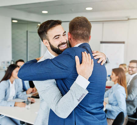 Coworkers hugging and celebrating in the office, or a happy young couple loveの写真素材