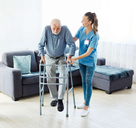 Doctor or nurse caregiver with senior man using walker assistanece  at home or nursing homeの写真素材