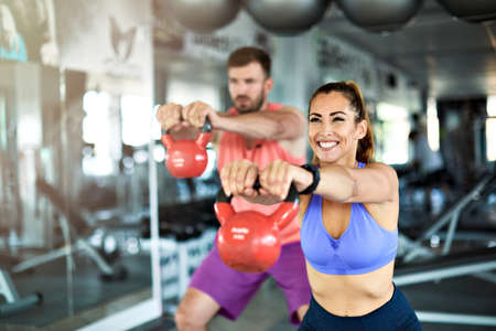 Happy healthy fit people at the gym exercising lifting kettlebellの写真素材
