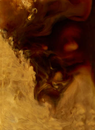 Close up of coffee and milk mixing in a glass cup backgroundの写真素材