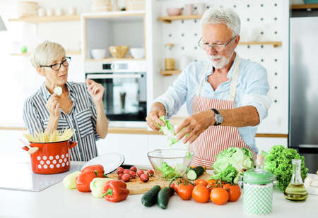 Portrait of happy senior couple prepering meal in kitchen