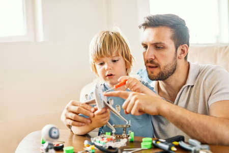 Portrait of a father and son, father teaching son to use tools and craftmenship with creative toy at homeの写真素材