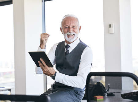 portrait of a senior businessman with a tablet in the officeの写真素材