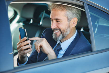 senior businessman sitting on the back sit of a luxury car