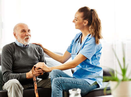 Doctor or nurse caregiver with senior man at home or nursing home