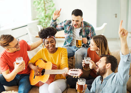 Young african woman playing guitar with friends at a partyの写真素材