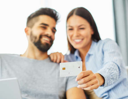 portrait of happy smiling young couple using tablet and a credit cardfor online shopping at homeの写真素材
