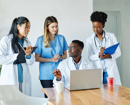 portrait of a doctors and nurses with laptop sitting by desk on their officeの写真素材