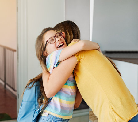 Portriat of a young teen school girl with backpack welcomed by her mother after coming back from school at homeの写真素材