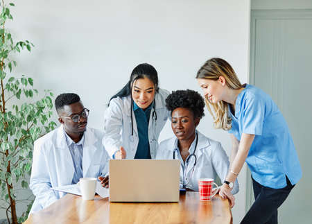 portrait of a doctors and nurses with laptop sitting by desk on their officeの写真素材