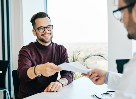 portrait of a young man holding papers or contract during a meeting in the office ot patient with doctor in hoispitalの写真素材
