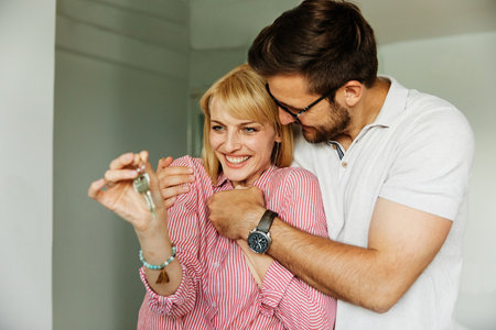 Happy young couple buying a new house receiving the keysの写真素材