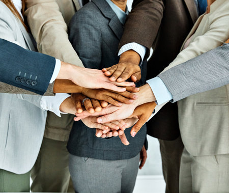 Portrait of a group of young and senior business people holding hands together in the office. Teamwork and success conceptの写真素材
