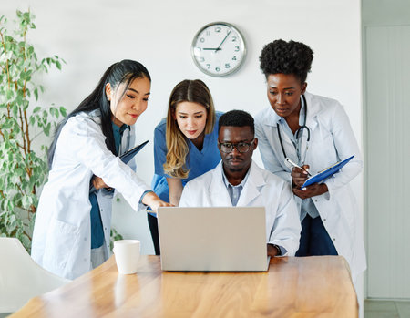 portrait of a doctors and nurses with laptop sitting by desk on their officeの写真素材