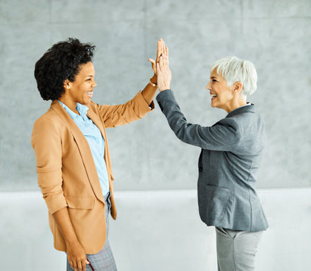 Group of young and senior business people having a meeting exchanging high five gesture introducing each other in the office. Teamwork and success conceptの写真素材