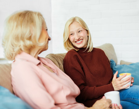 Portrait of happy mother and daughter or grandmother and granddaughter having fun and having conversation at homeの写真素材