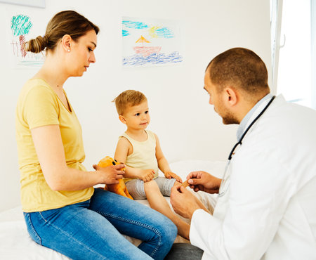 Doctor with a little boy and his mother or nurse in doctors office in clinicの写真素材