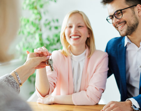 Happy young couple buying a new house receiving the keysの写真素材