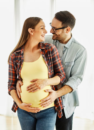 Happy young couple hugging and bonding, pregnent woman, father having fun holding stomach to baby at...