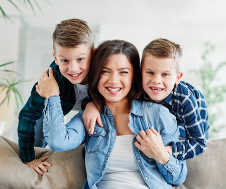 Shot of two adorable little boys affectionately kissing their mother at homeの写真素材