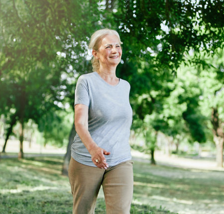 Smiling active senior woman jogging running and walking doing fitness in the parkの写真素材