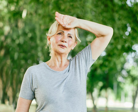 Portrait of a happy active beautiful senior woman holding a bottle of water posing after exercicing outdoorsの写真素材
