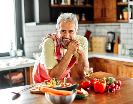 Portrait of happy senior man prepering meal in kitchenの写真素材