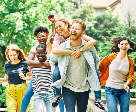 Group of young happy people or students having fun together outdoors in street or park or outside...