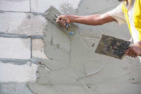 "Mason plastering the concrete to build wall, Construction under building with mason plastering concrete to brick wall"の写真素材