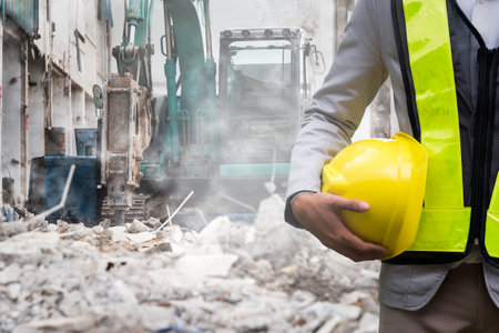 Engineer or Safety officer holding hard hat with the heavy equipment excavator demolition demolish machine in construction site.の写真素材
