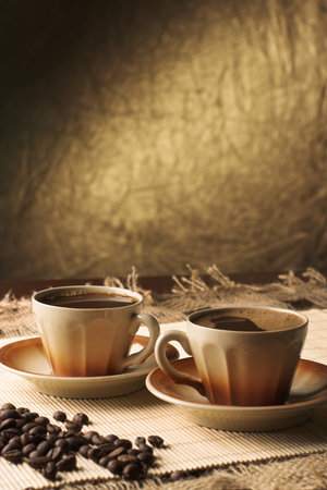 Two cups of coffee with coffee beans on a wooden table. Toned.の写真素材