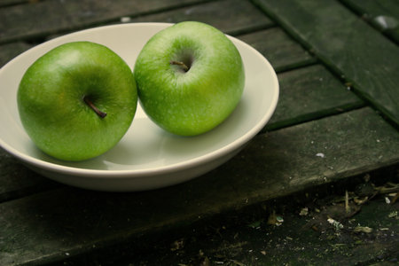 two green apples on a white plateの写真素材