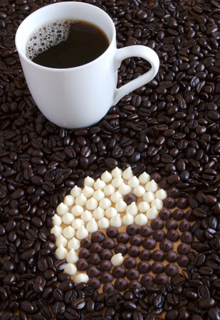 Coffee cup with white chocolate chips and milk chocolate chips forming a yin yang symbol.の写真素材