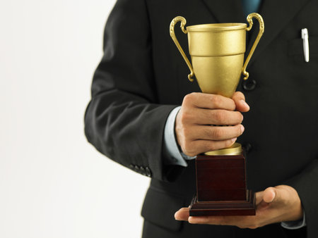 a winner with suit holding a trophyの写真素材