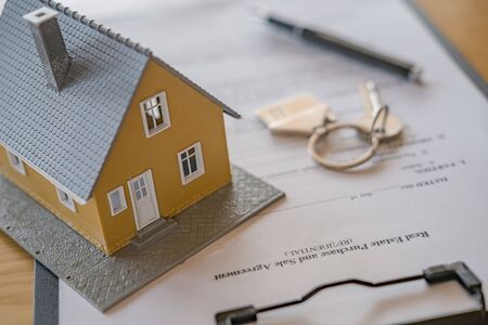 Desk of real estate agent with house model, key, pen on contract document and calculator for...