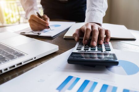Close-up of businessman hand using calculator to calculate business data, accountancy document at home office.の写真素材
