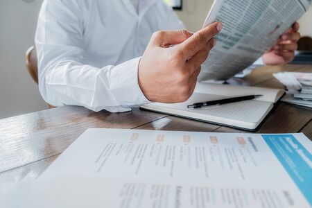Young unemployed is searching for a job in the newspaper and laptop. Interview the job and hiring...