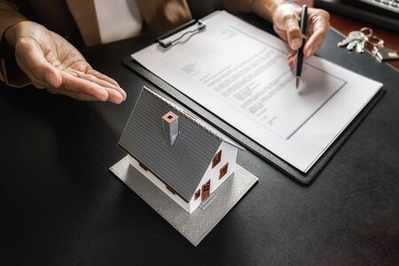 House model with agent asking costumer for contract to buy, get insurance or loan real estate or property.の写真素材