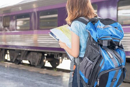 Woman traveler tourist with luggage at train station. Traditional train for transportation.の写真素材