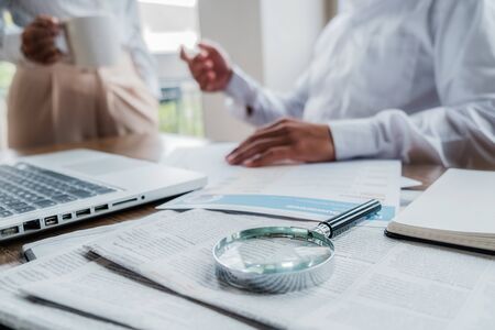 Young unemployed is searching for a job in the newspaper and laptop. Interview the job and hiring concept.の写真素材