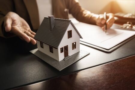 House model with agent asking costumer for contract to buy, get insurance or loan real estate or property.の写真素材