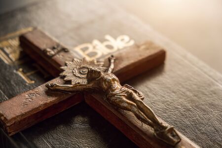 Closeup of wooden Christian cross on Bible, vintage tone. Symbol of God and goodness.の写真素材