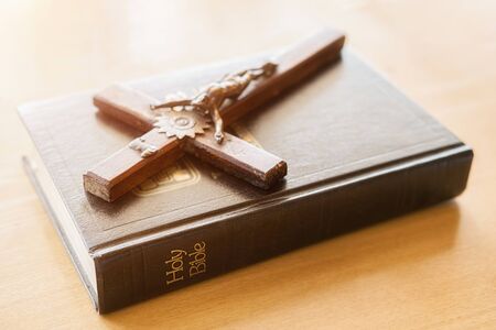 Christian woman praying with hands together on holy bible and wooden cross. Woman pray for god...