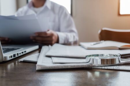 Young unemployed is searching for a job in the newspaper and laptop. Interview the job and hiring concept.の写真素材