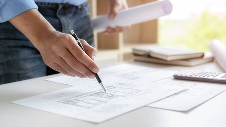Architect or Engineer working in office with engineering tools, blueprint and building model....