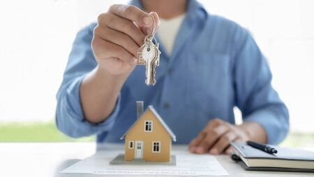 Real estate agent holding a key and asking costumer for contract to buy, get insurance or loan real estate or property.の写真素材